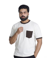 A man wearing a white ringer t-shirt with dark brown trim on the crew neck, sleeve cuffs, and a matching chest pocket, paired with dark pants, shot against a plain white background.